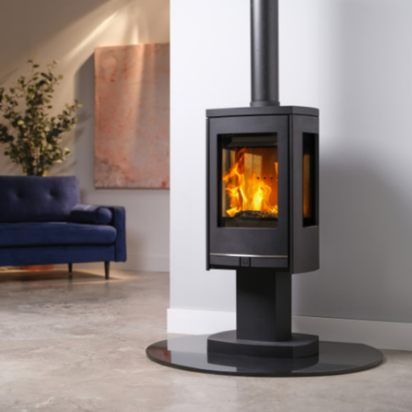 Capital Fireplaces Athena Pedestal Eco Wood Stove. ECO 2022 DEFRA Approved wood stove features a striking pedestal base and three expansive glass viewing windows, at The Stove House Ltd. West Sussex. 