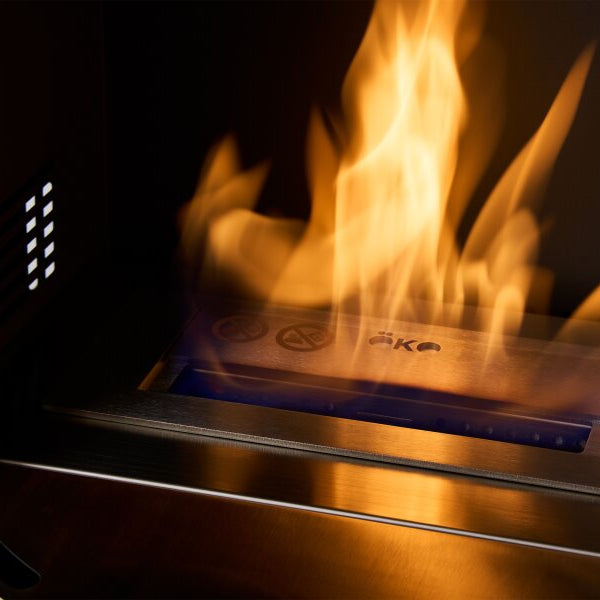 A close-up of an oko S5 internal stove chamber fireplace or stove with a bright orange-yellow flames rising upward in a dark interior.